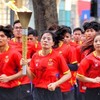 Vietnamese runner Nguyen Thi Huyen, who is multi-time SEA Games winner, and outstanding Vietnamese athletes carry the torch around the Hoan Kiem Lake area. (Photo: VNA)