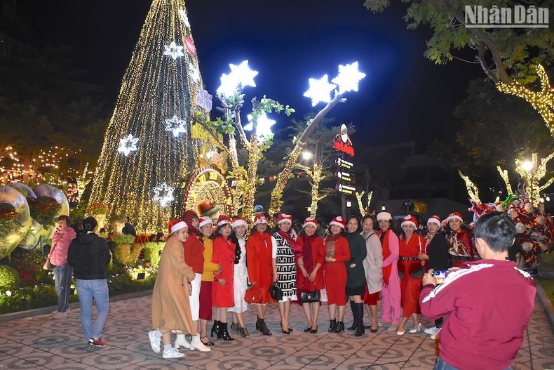 Women wearing Santa hats pose for a group photo in front of a Christmas tree in Da Nang City.