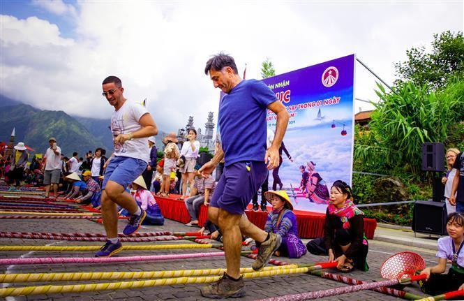 Foreign tourists join bamboo pole dance at a cultural event in Sa Pa town, Lao Cai province (Photo: Vietnam Pictorial)