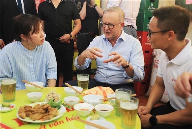 Australian Prime Minister Anthony Albanese talks about Vietnamese dishes at the lunch with young people. (Photo: VNA)