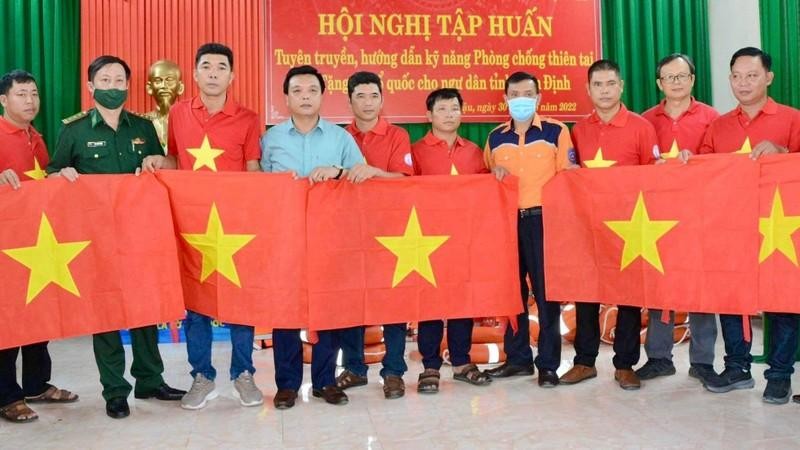 Representatives of Nguoi Lao Dong Newspaper, the Nam Dinh provincial fisheries sub-department and the Maritime Search and Rescue Coordination Centre for Zone 1 present flags to the fishermen.