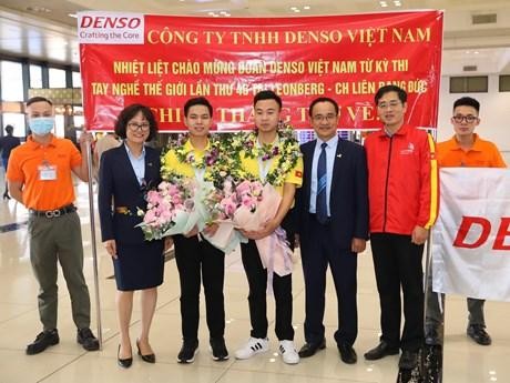 Nguyen Xuan Thai (third from left) and Nguyen Thanh Tung (centre) are welcomed when they return to Vietnam. (Photo: VNA)