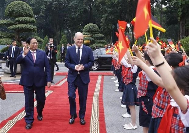Children welcome German Chancellor Olaf Scholz (R) at the official welcome ceremony in Hanoi on November 13. (Photo: VNA)