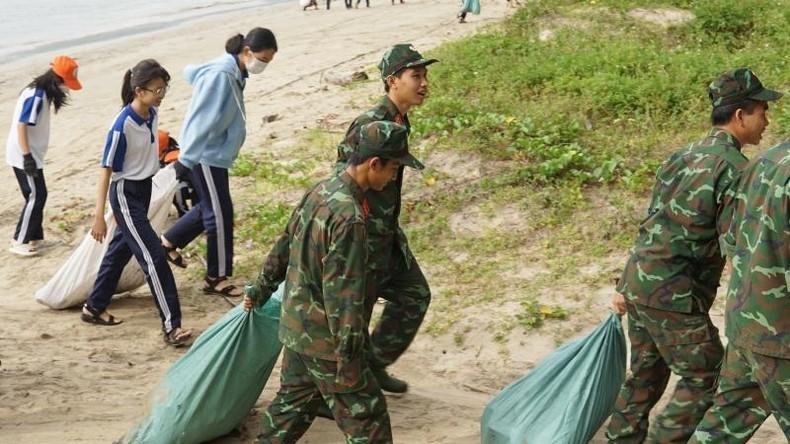 Students, officers and soldiers stationed on the island collect garbage at the beach.