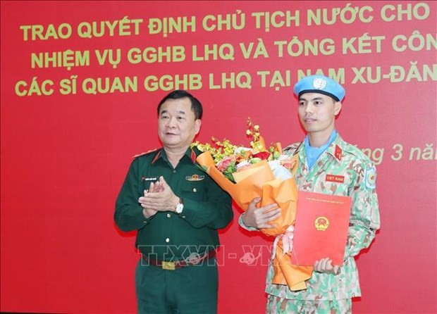 Deputy Minister of National Defence Sen. Lt. Gen. Hoang Xuan Chien hands over the President's Decision to Maj. Nguyen Van Phong, former assistant at the political affairs division of Engineer Brigade 229 at the event. (Photo: VNA)