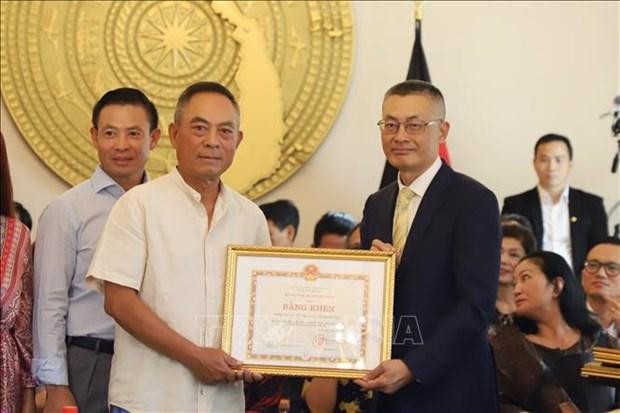 Vietnamese Ambassador to Germany Vu Quang Minh (R) presents the Foreign Minister's certificates of merit to a representative of Dong Xuan Centre in Berlin. (Photo: VNA)