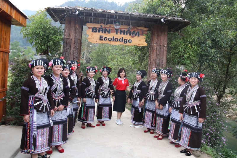 Lu ethnic women dressed in traditional costumes pose for a photo with a tourist at the entrance of Ban Tham Ecolodge Homestay (Photo: dulich.laichau.gov.vn)