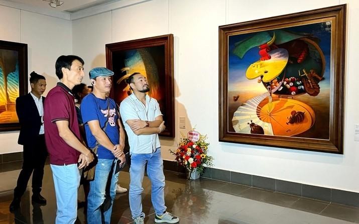 Painter Le Thanh Binh (first from left) introduces his paintings to visitors at the exhibition.