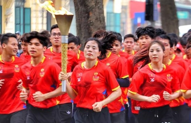 Vietnamese runner Nguyen Thi Huyen, who is multi-time SEA Games winner, and outstanding Vietnamese athletes carry the torch around the Hoan Kiem Lake area. (Photo: VNA)