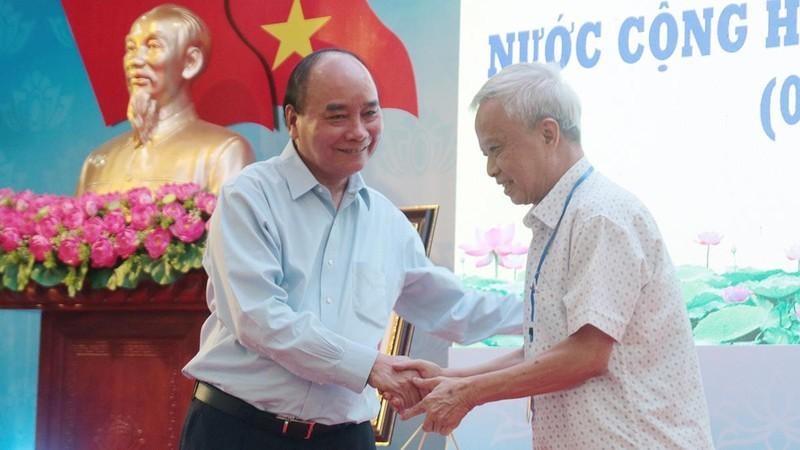 President Nguyen Xuan Phuc presents gifts to a retired official (Photo: NDO)