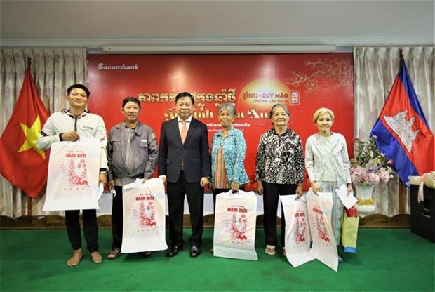Vietnamese Ambassador to Cambodia Nguyen Huy Tang gives presents to representatives of families that contributed to national revolution and community. (Photo: VNA)