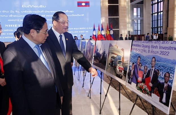 Prime Ministers Pham Minh Chinh (L) and Sonexay Siphandone visit the photo exhibition in Vientiane on January 12. (Photo: VNA)