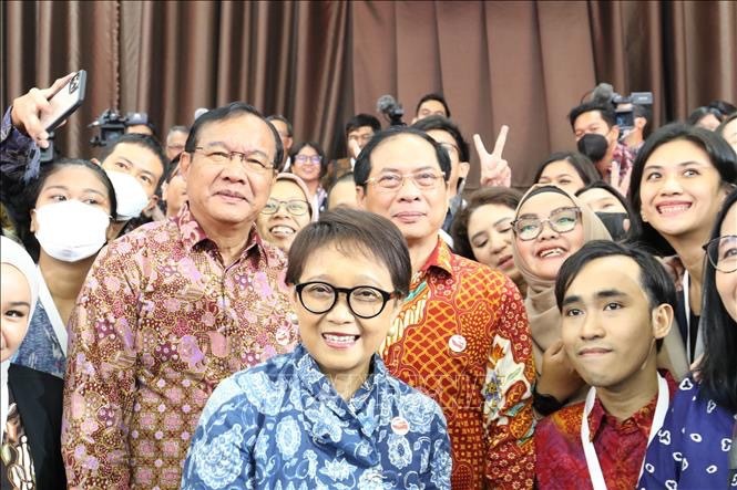 Foreign Minister Bui Thanh Son (C, red shirt) and his Lao, Indonesian counterparts posing for a photo with reporters at ASEAN Foreign Ministers’ Retreat. (Photo: VNA)