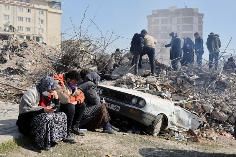 People sit as others search amid the rubble in the aftermath of a deadly earthquake in Kahramanmaras, Turkey. (Photo: Reuters)