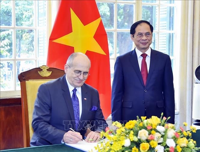 Polish Minister of Foreign Affairs Zbigniew Rau (left) writes in the guestbook. (Photo: VNA)