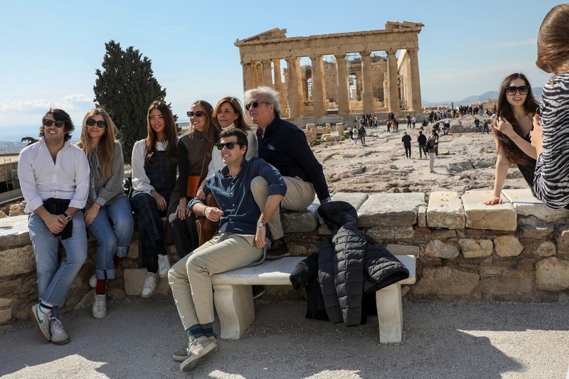 Visitors pose for a photo with the ancient Parthenon Temple seen in the background, atop the Acropolis hill archaeological site in Athens, Greece. (Photo: REUTERS)