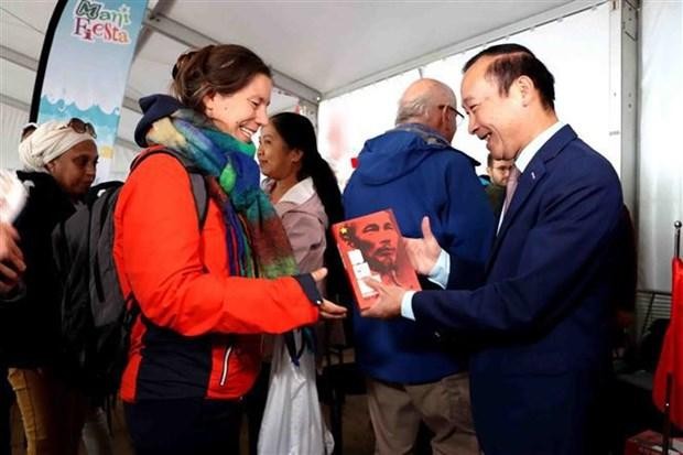 Vietnamese Ambassador to Belgium Nguyen Van Thao presents a book about late President Ho Chi Minh to a foreign reader at Manifesta 2022 (Photo: VNA)