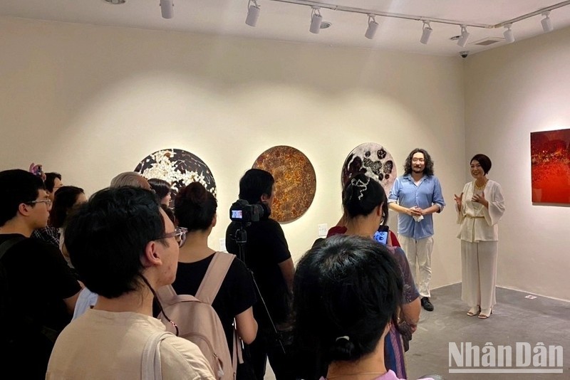 Artist Ando Saeko (white shirt) talks with visitors at the exhibition.