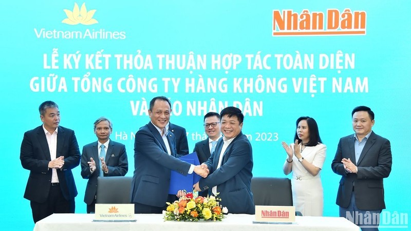 Deputy Editor-in-Chief of Nhan Dan Newspaper Que Dinh Nguyen and Member of the Board of Management and General Director of Vietnam Airlines Le Hong Ha exchange the cooperation agreement in the presence of leaders of the two agencies.