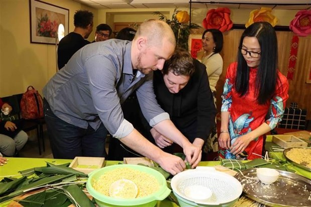 Belgian friends are learning how to make "Banh chung" at the event. (Photo: VNA) 