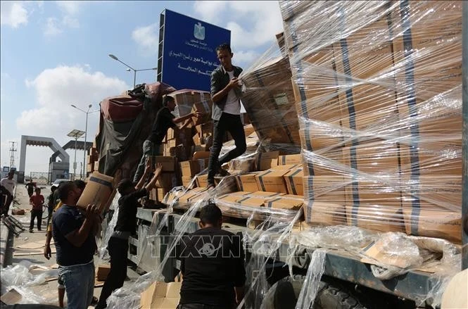 People deliver humanitarian aid goods at the Rafah Border Crossing in the Gaza Strip. (Photo: Xinhua/VNA)
