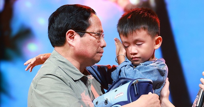 PM Pham Minh Chinh gives encouragement to a boy named Nguyen Quoc Bao, whose father and elder sister were washed away by a flood while the three were crossing a bridge in Cau Treo hamlet of Yen Thuan commune, Ham Yen district, Tuyen Quang province. (Photo: VNA)