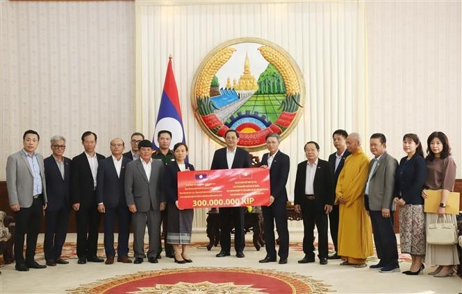 The delegation of the Vietnamese community in Laos presents to the Lao side a token of their aid for those affected by Typhoon Yagi in the country’s northern region. (Photo: VNA)