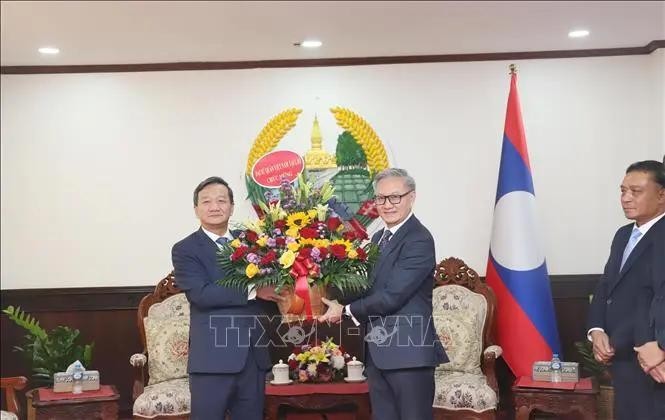 Ambassador Nguyen Minh Tam (left) present flowers to congratulate Lao Foreign Minister Thongsavanh Phomvihane on the 49th anniversary of Laos' National Day. (Photo: VNA) 