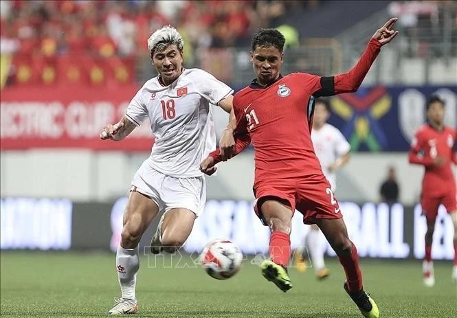 Thanh Binh (white's dribbling is fiercely blocked by a Singaporean defender at the first leg of the ASEAN Cup semifinal on December 26. (Photo: VNA) 