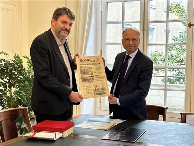 Deputy Mayor of Nantes city Aymeric Seassau (L) presents Ambassador Dinh Toan Thang with the original versions of two local newspapers that were issued in November 1968 and featured articles showing support for Vietnam in the fight against the US imperialists. (Photo: VNA)