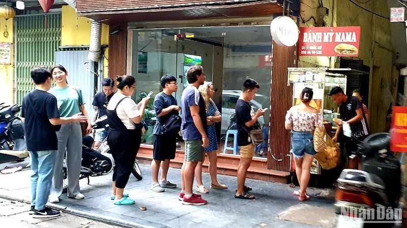 Foreign tourists stand in line to buy bread at a shop on Ly Quoc Su Street, Hanoi. (Photo: T.LINH)