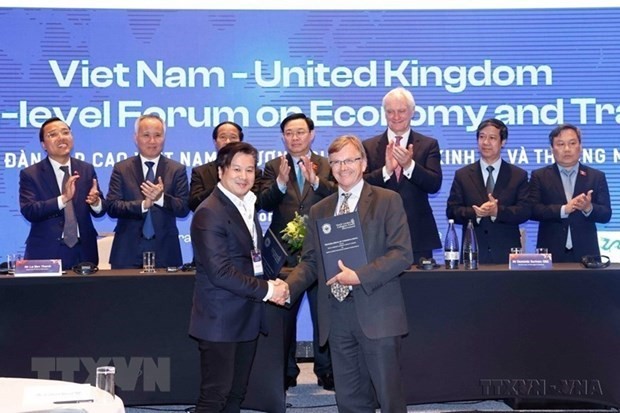 Chairman of the Vietnamese National Assembly Vuong Dinh Hue (behind, centre) witnesses the exchange of cooperation agreements between businesses and localities of Vietnam and the UK at a high-level forum on economy and trade between the two countries in London in June 2022. (Photo: VNA)