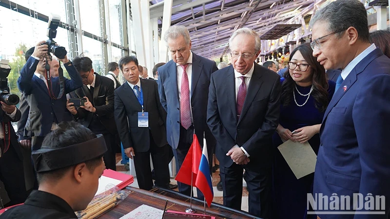 Ambassador Dang Minh Khoi, Russian Deputy Foreign Minister Mikhail Galuzin, and Chairman of the Committee for External Relations of St. Petersburg Evgeny Grigoriev watch calligraphy at the ceremony marking 78th anniversary of Vietnam's National Day in Russia. (Photo: XUAN HUNG)