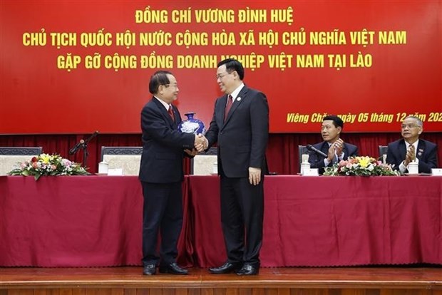 NA Chairman Vuong Dinh Hue (R) shakes hands with a representative of Vietnamese enterprises in Laos. (Photo: VNA)