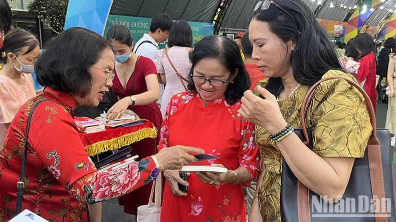 Dr. Quach Thu Nguyet, Ambassador of Reading Culture of Ho Chi Minh City, offers books to tourists as Tet gifts.