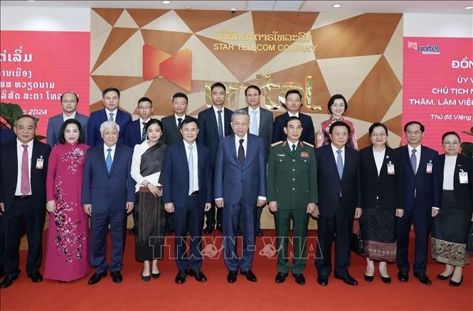 President To Lam (middle, first row) takes a group photo with representatives of Star Telecom (Unitel) as part of his state visit to Laos on July 11. (Photo: VNA)