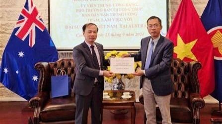 Ambassador Pham Hung Tam (R) hands over 12,700 AUD (8,700 USD) to the delegation to help victims of Typhoon Yagi (Photo: VNA)