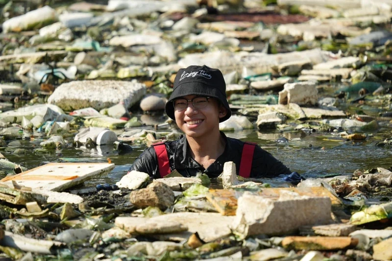 A volunteer of Green Saigon "dives" into waste to clean up a polluted canal.