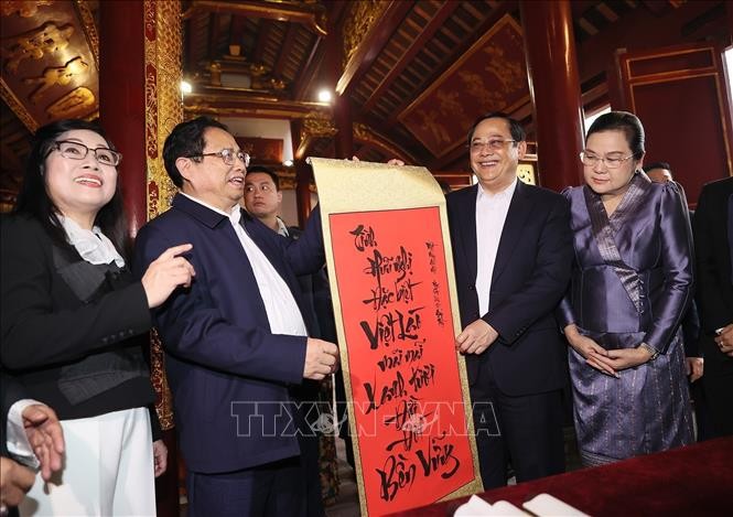 PM Pham Minh Chinh (second, left) presents Lao PM Sonexay Siphandone a calligraphy with Vietnamese words which read Vietnam-Laos friendship is forever green and solid for generations (Photo: VNA)