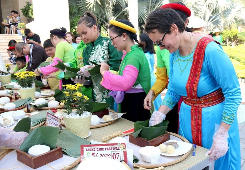 Foreigners try their hands at making 'banh chung' (square glutinous rice cake), an indispensable dish of Vietnamese people during Tet Festival. (Photo: VNA)