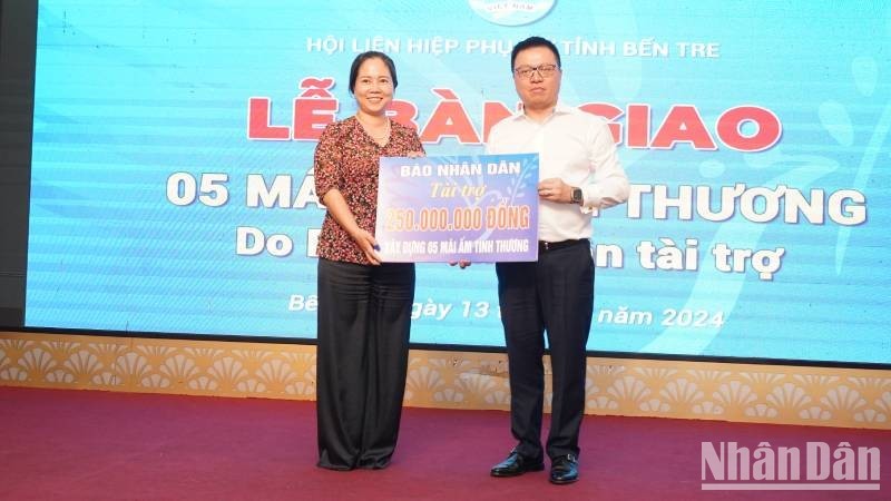 Nhan Dan Newspaper Editor-in-Chief Le Quoc Minh hands over the funding of construction of five social houses to a representative of the Ben Tre provincial Women’s Association.