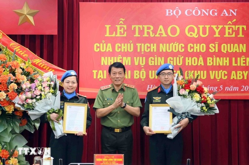 Deputy Minister of Public Security Sen. Lt. Gen. Luong Tam Quang (centre) presents the State President's decisions to the two officers on May 29. (Photo: VNA)