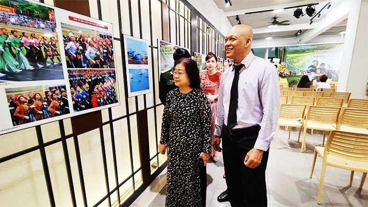 Photographer Nguyen A introduces his works to former Vice President Truong My Hoa at his ‘70 years of Dien Bien Phu Victory - The resounding heroic song’ photo exhibition in Ho Chi Minh City.