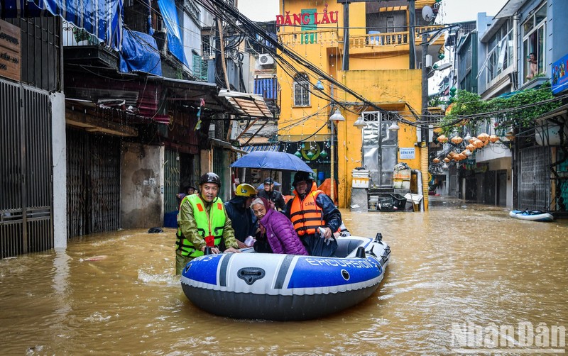 Police officers helped an old woman in Phuc Tan Ward, Hoan Kiem District, Hanoi reach a safer area.