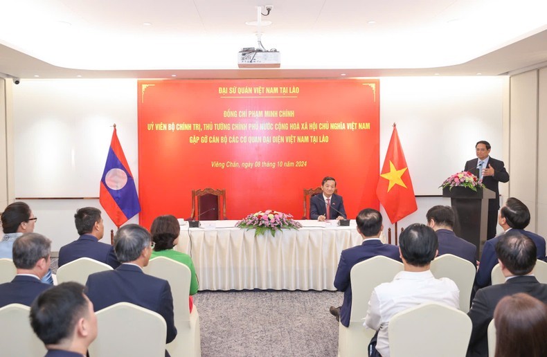 Prime Minister Pham Minh Chinh (standing) speaks at the meeting with staff of the Vietnamese Embassy and Vietnamese representative agencies in Laos on October 8. (Photo: VGP).