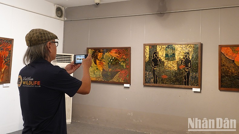 A visitor taking photos of paintings on display at the exhibition 