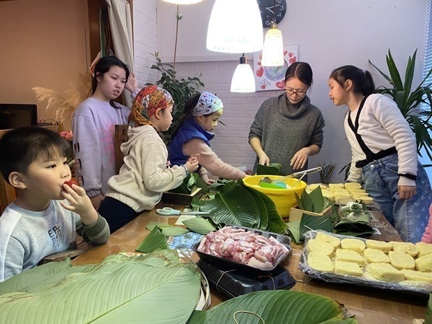 Children learn to make 'banh chung' (square glutinous rice cake), a traditional dish of Vietnamese people during the Tet (Lunar New Year) festival. (Photo: VNA)