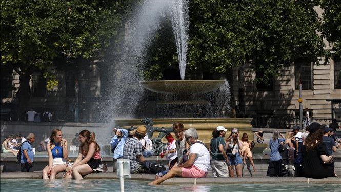 People avoid the heat by a fountain at Trafalgar Square in London on June 17, 2022. (Photo: AFP/VNA)