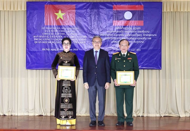 Thongsavanh Phomvihane ̣(centre), Chairman of the LPRP Central Committee’s Commission for External Relations, presents the Friendship Medal to two individuals of the board of health protection and care for central officials and Central Military Hospital 108 on February 25. (Photo: VNA)
