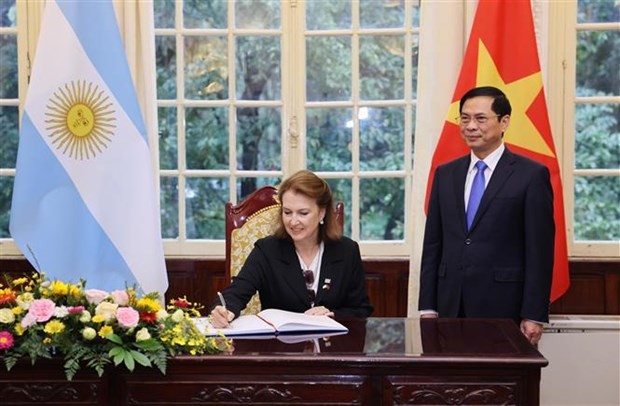 Argentina’s Minister of Foreign Affairs, International Trade and Worship Diana Elena Mondino writes in a guestbook in the witness of Foreign Minister Bui Thanh Son. (Photo: VNA)